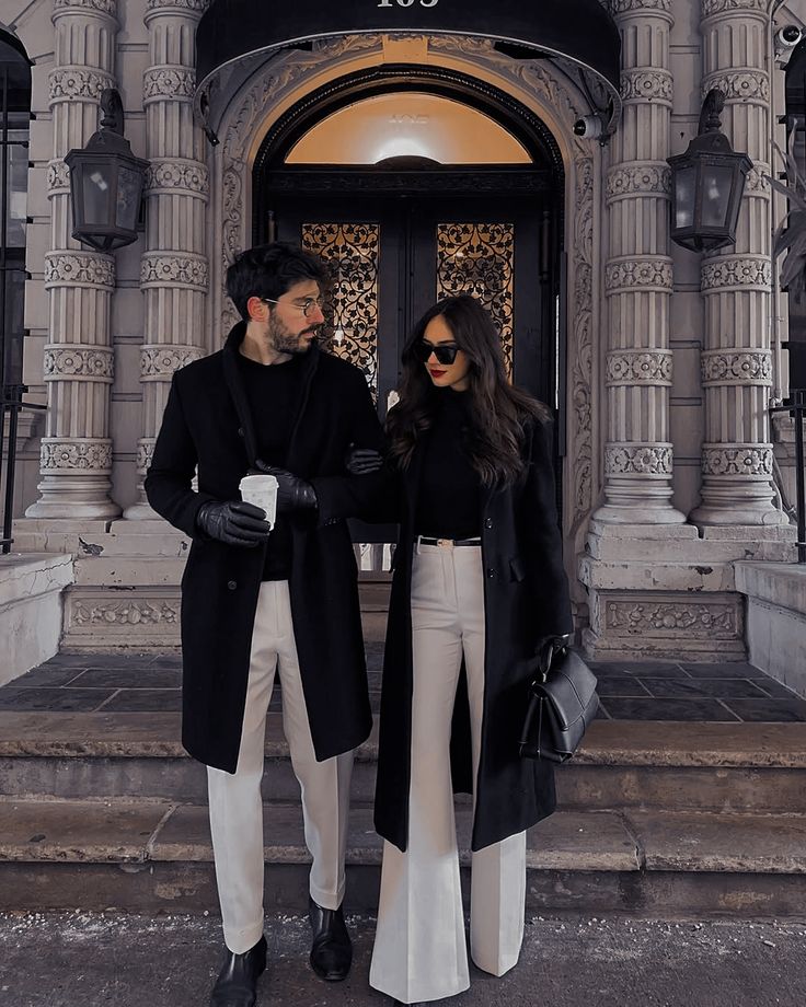 Black wool coats with cream trousers outside a carved stone doorway