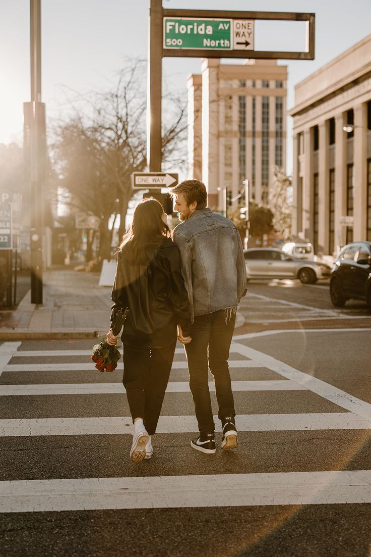 Couple walking a city crosswalk at golden hour with roses
