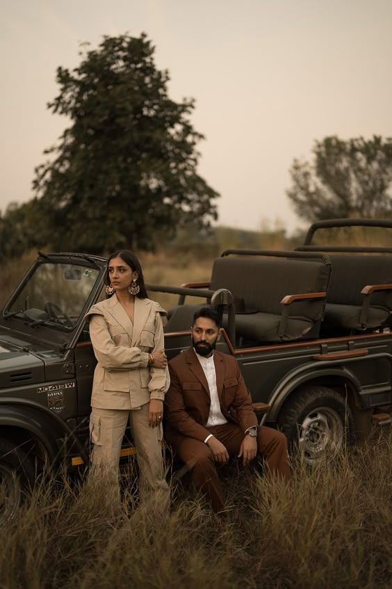 Beige safari jacket and rust suit beside a dark green jeep at golden hour