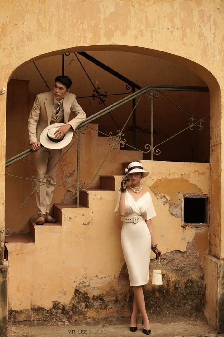 Beige suit with a belted ivory midi dress against an aged colonial wall