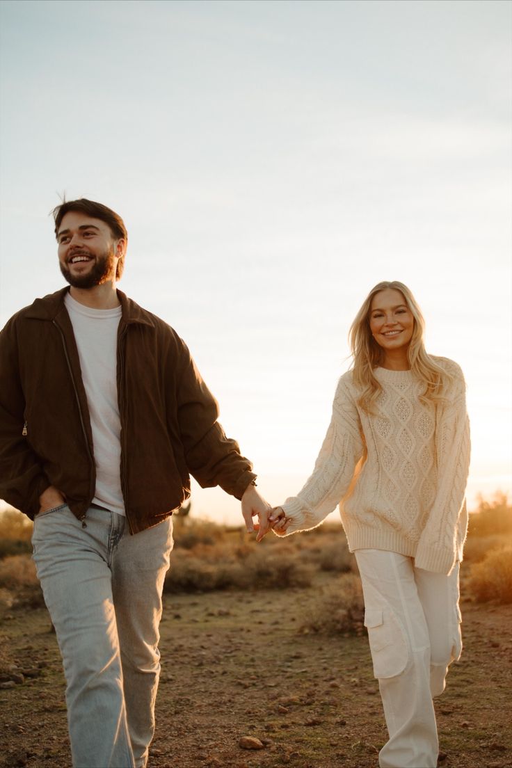 Brown jacket and cream cable knit walking through golden desert light