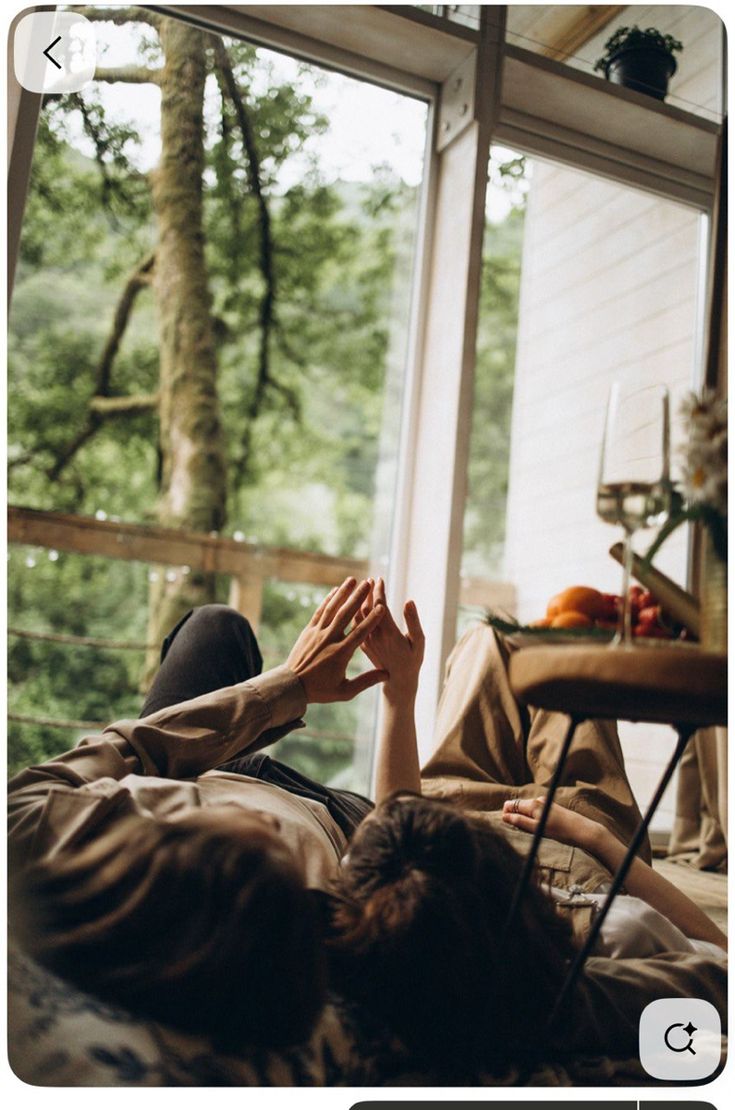 Hands touching by a sunlit window with forest view