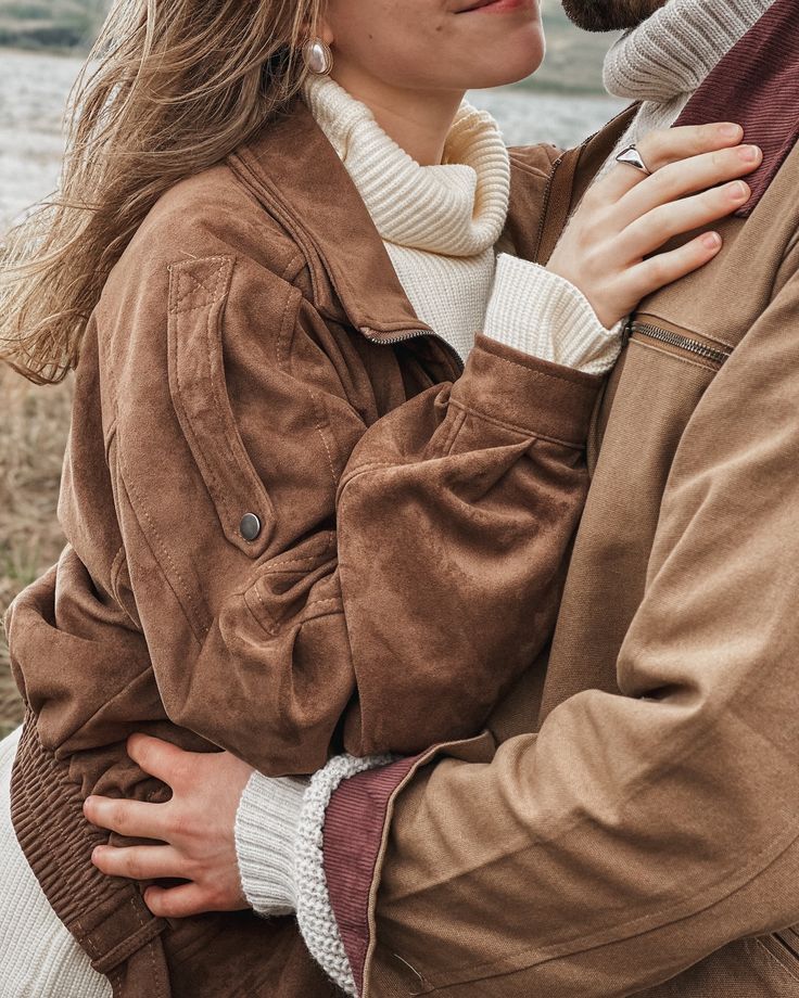 Suede jackets layered over cream turtlenecks by the water