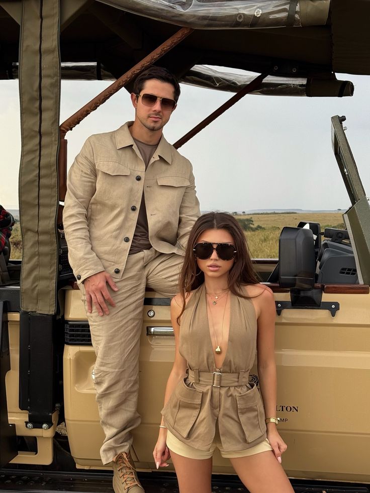 Matching beige utility safari outfits by an open-air safari vehicle